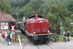 Eine altrote V 100 mit Reichsbahnwagen verlässt gerade den Bf Hinterweidenthal Ort. Das Signal Zs 12 (M-Tafel) erlaubt die Vorbeifahrt am Halt zeigenden Asig (Foto: ZSPNV Süd)